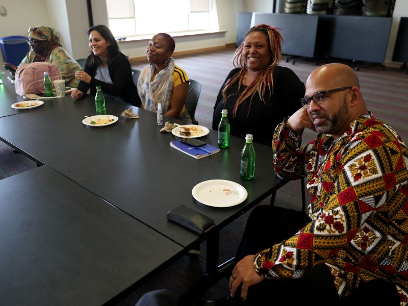 A group of community journalists sit at a table to listen to speakers.