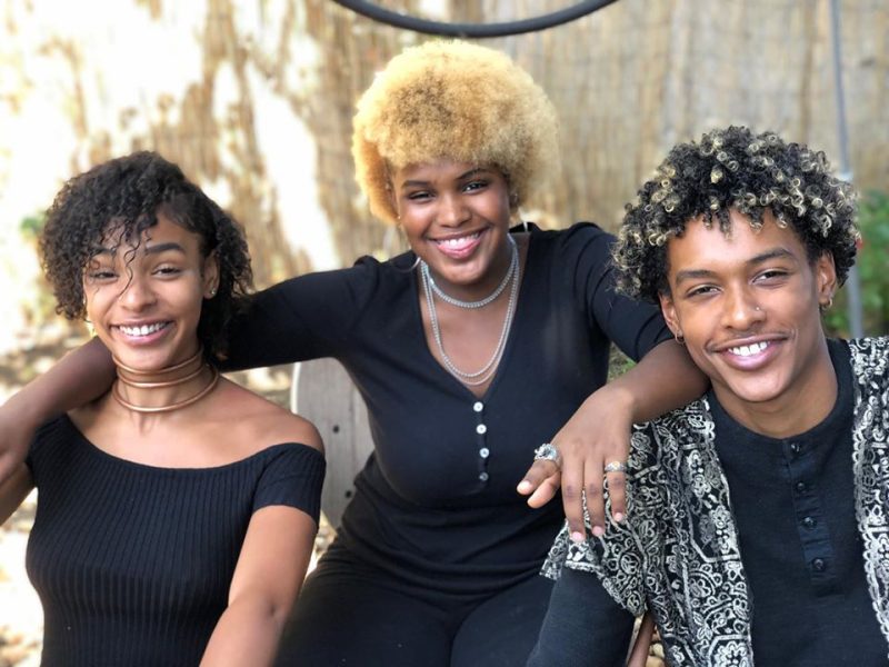 Three African American teenagers pose for a photo.