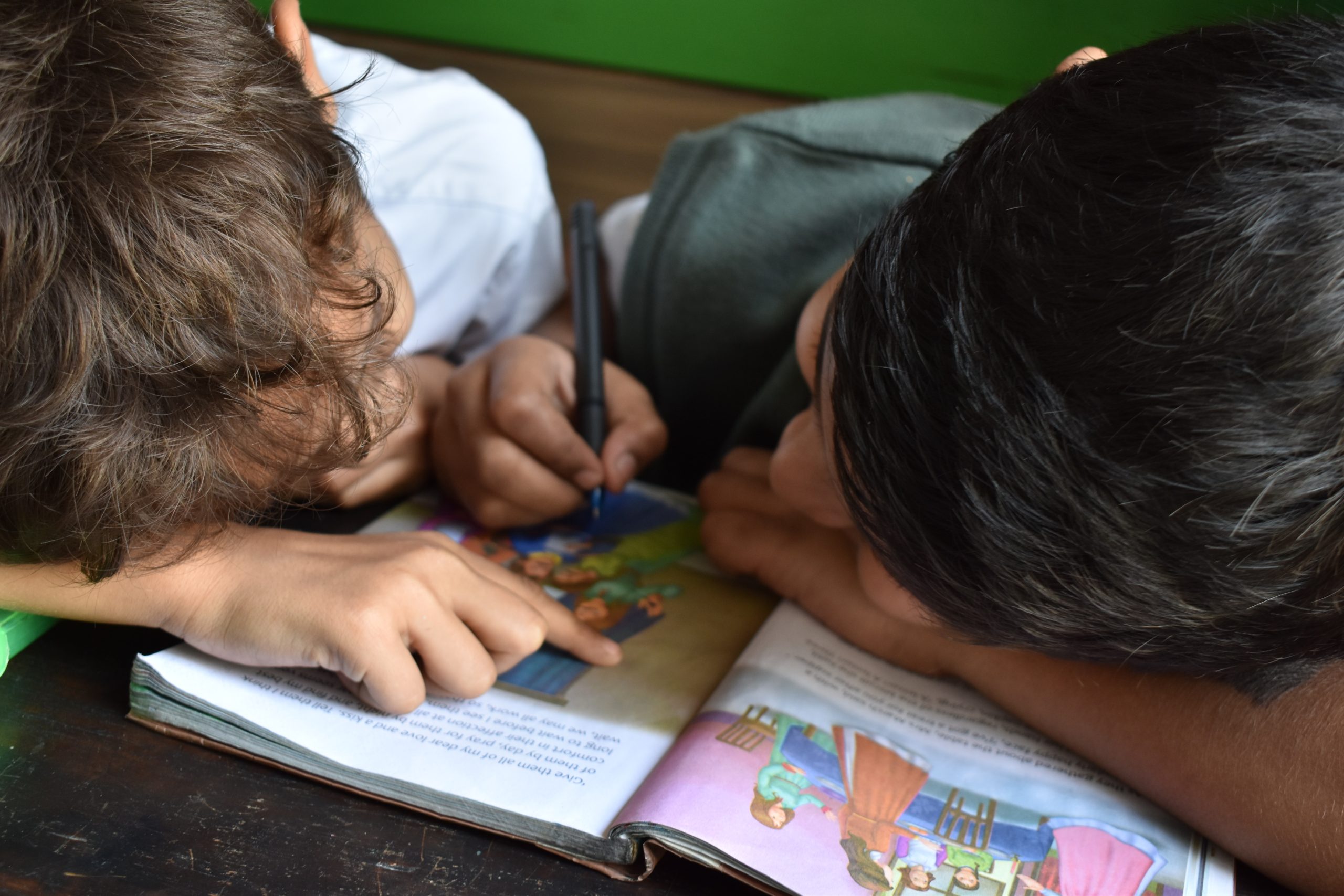 A bird's eye view of two children reading a textbook.