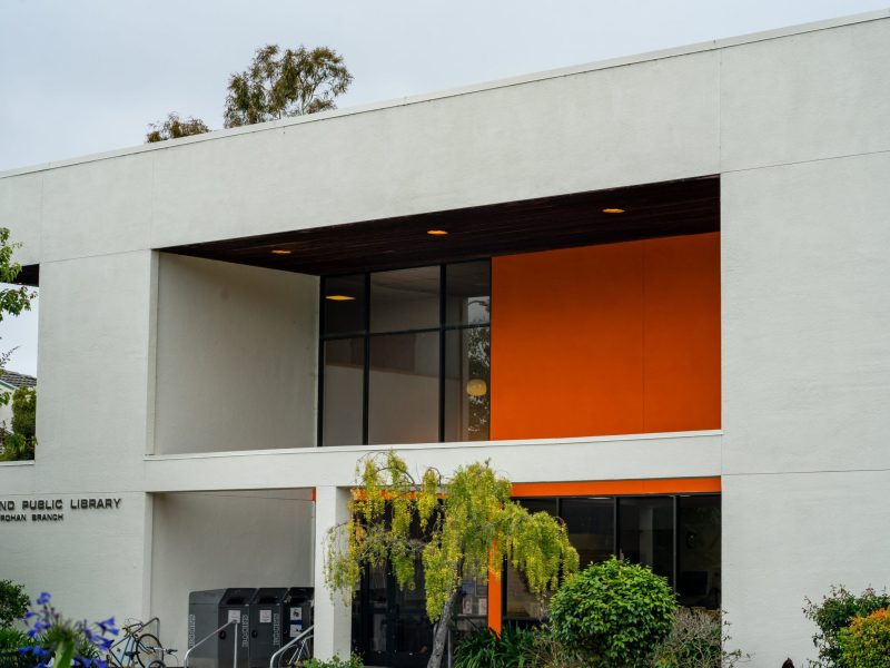 A image of the outside of a white and orange library in Oakland.