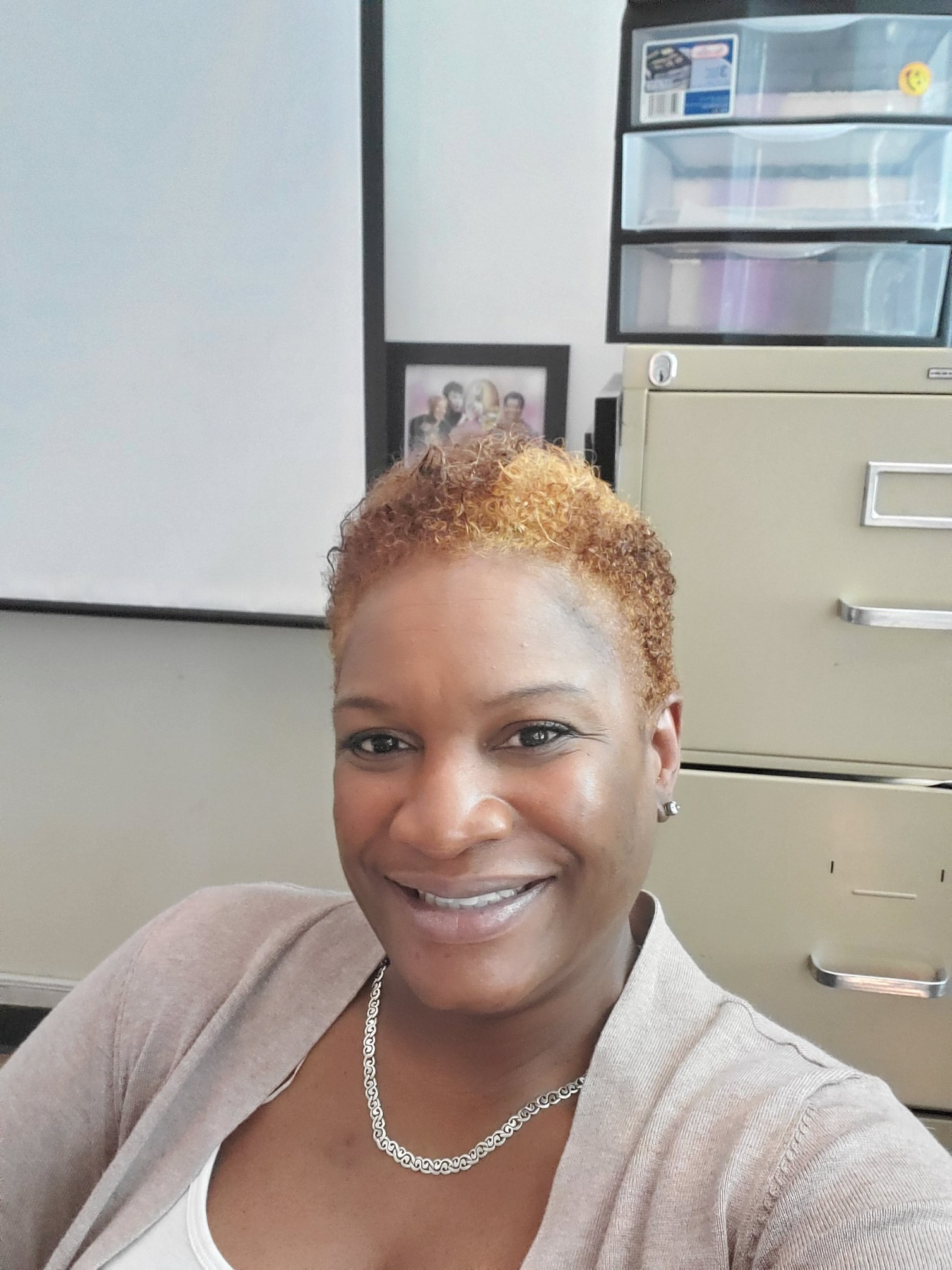 An African American woman with short redish hair smiles at camera.