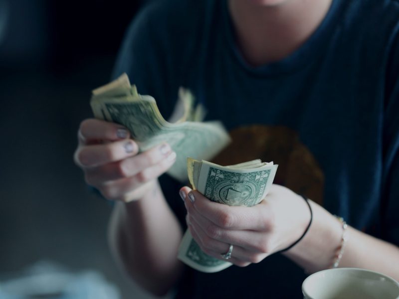 A close up of a person counting dollar bills.