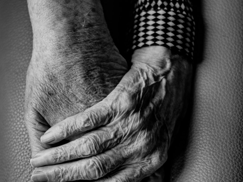 A black and white photo of older people holding hands.