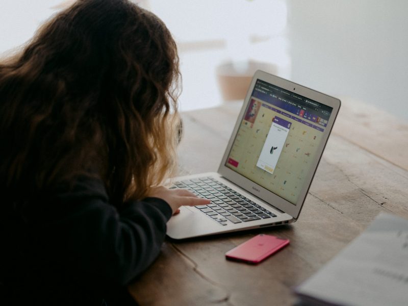 An image of a curly haired girl looking at her laptop.