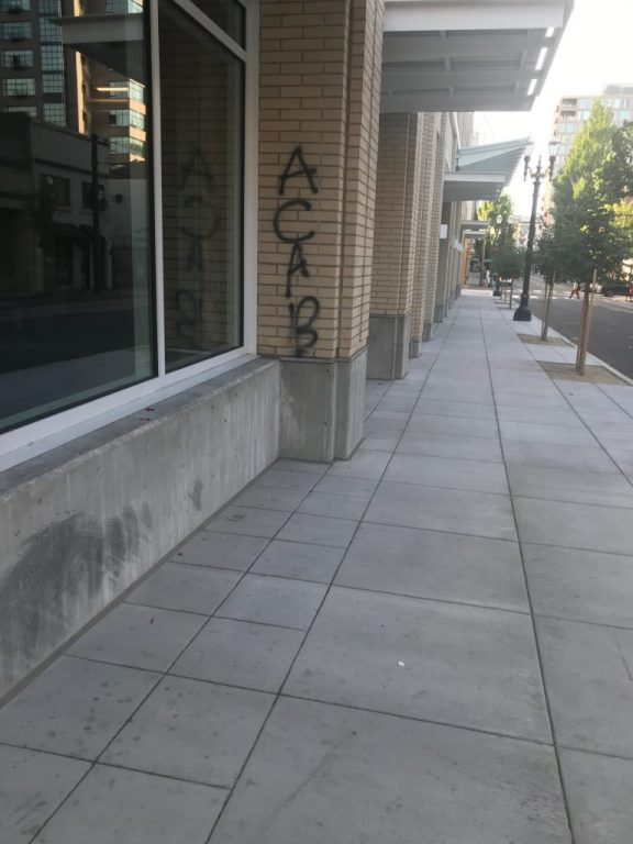 A nondescript beige wall has the words "ACAB" graffitied on it.