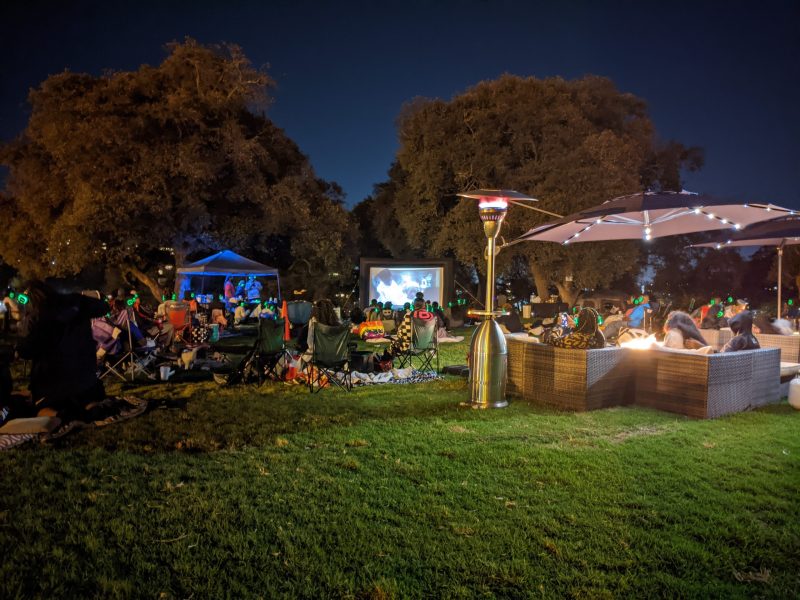 a night time scene at Lake Merritt, where people are watching a film outside.