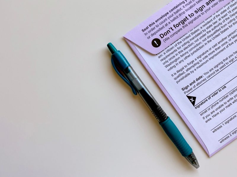 A mail in ballot next to a blue pen.