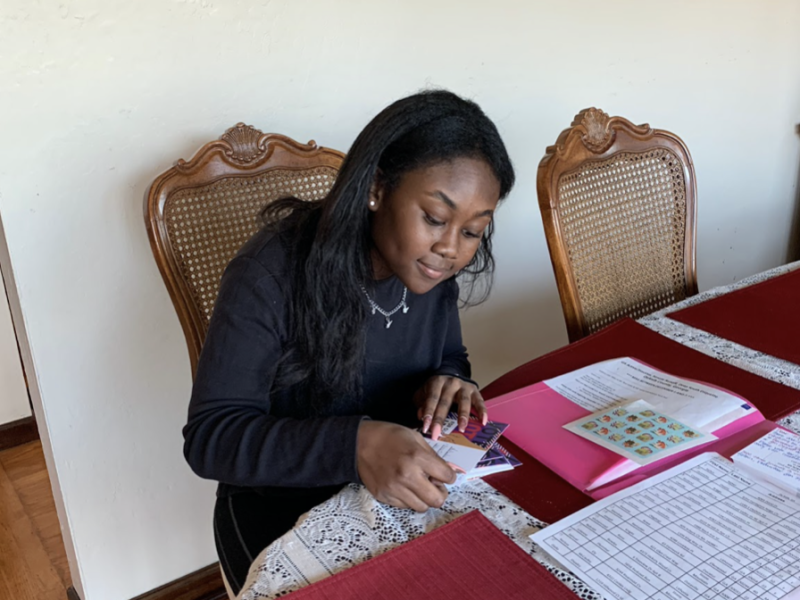 An African American woman puts stamps at the dining table.