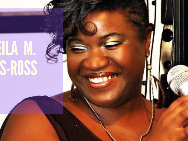 An image pf a smiling African American woman in front of a mic.