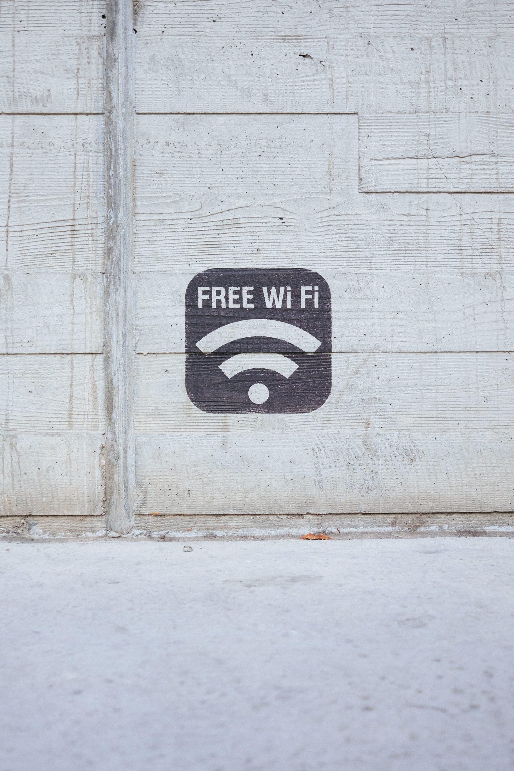 a stencil painting that says "free wifi" against concrete backdrop.
