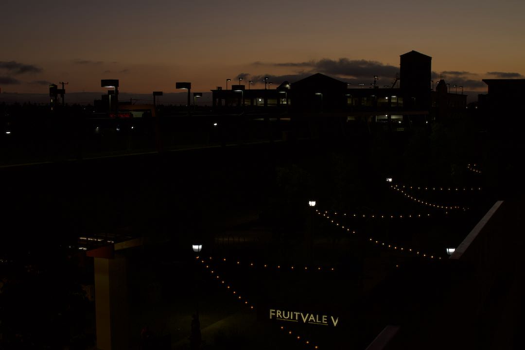 An image of the night sky in Fruitvale, Oakland. All is dark except a few lights from the homes and "Fruitvale" sign.