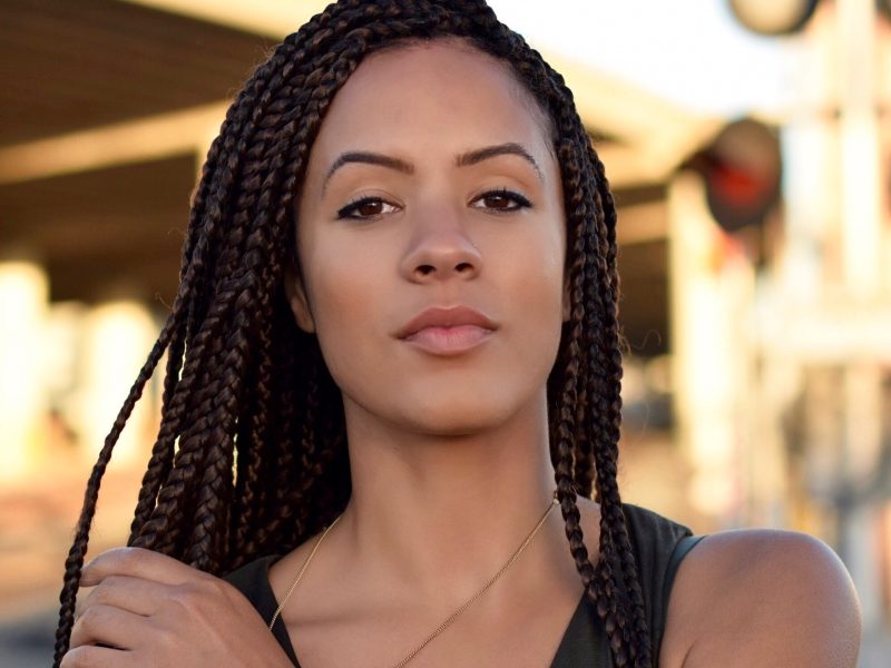 An image of an African American woman with braids standing outside.