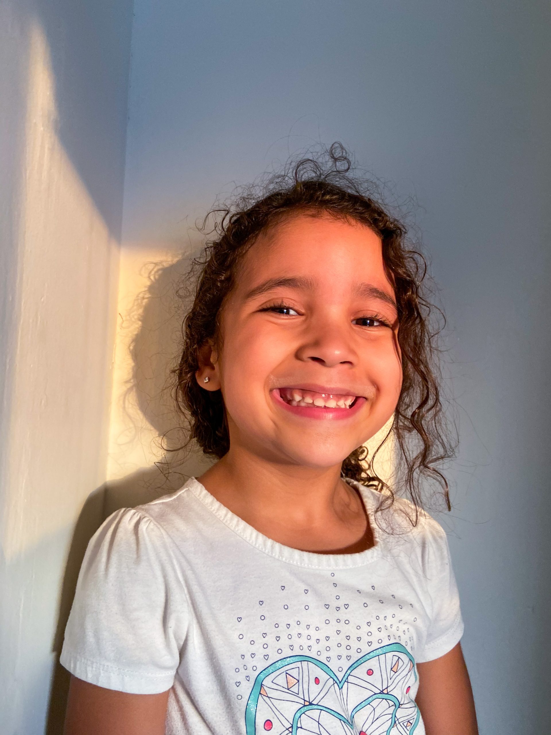 a young girl with curly hair smiles at the camera