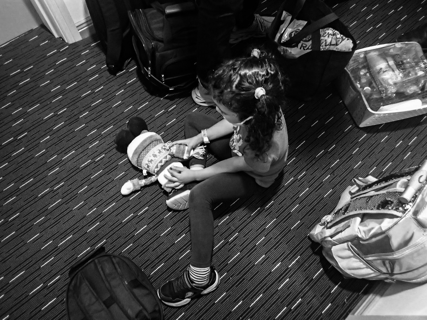 a black and white photo of young girl playing on the floor with a doll