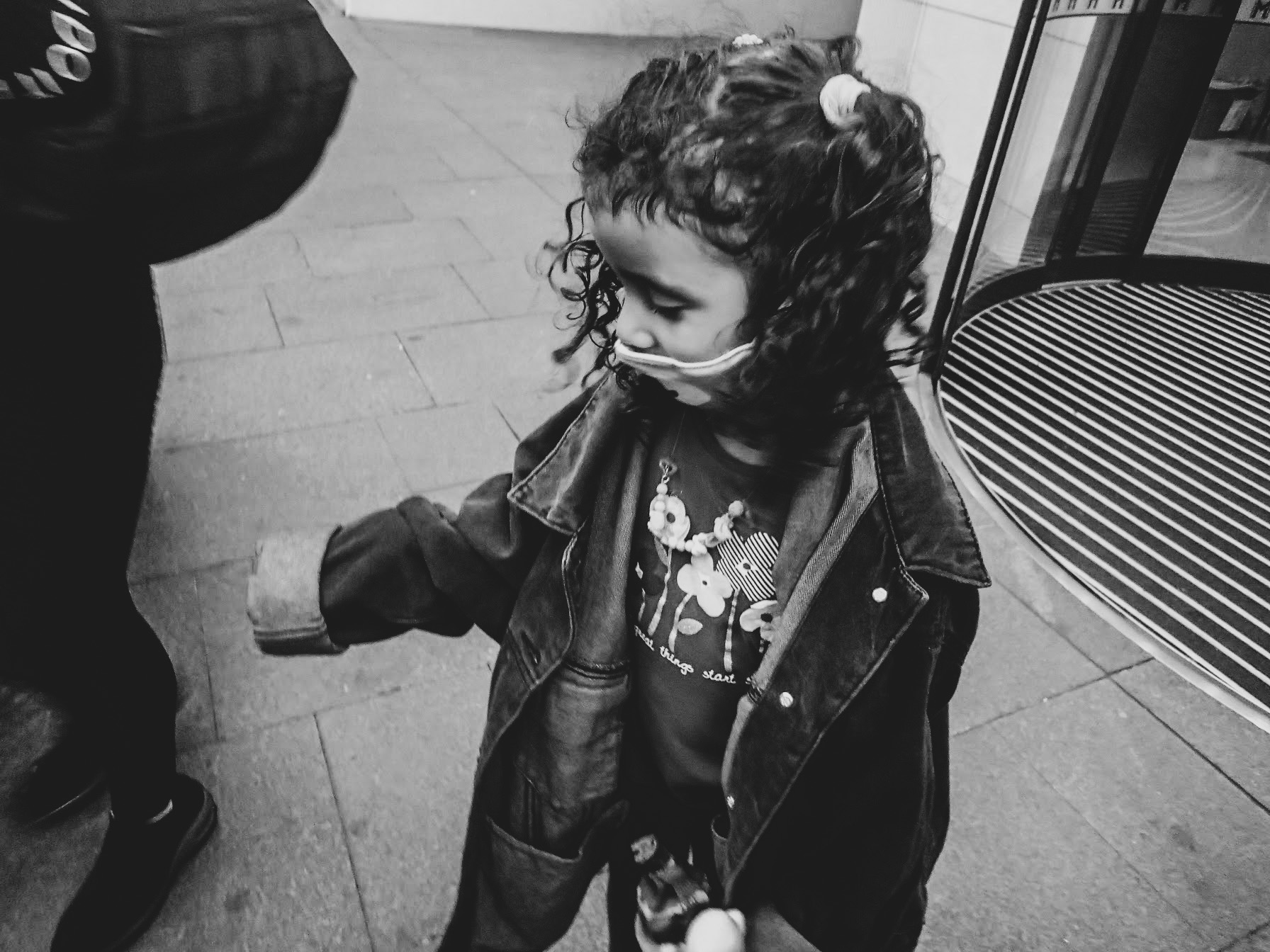 a black and white photo of girl with curly pigtails wearing oversized jacket