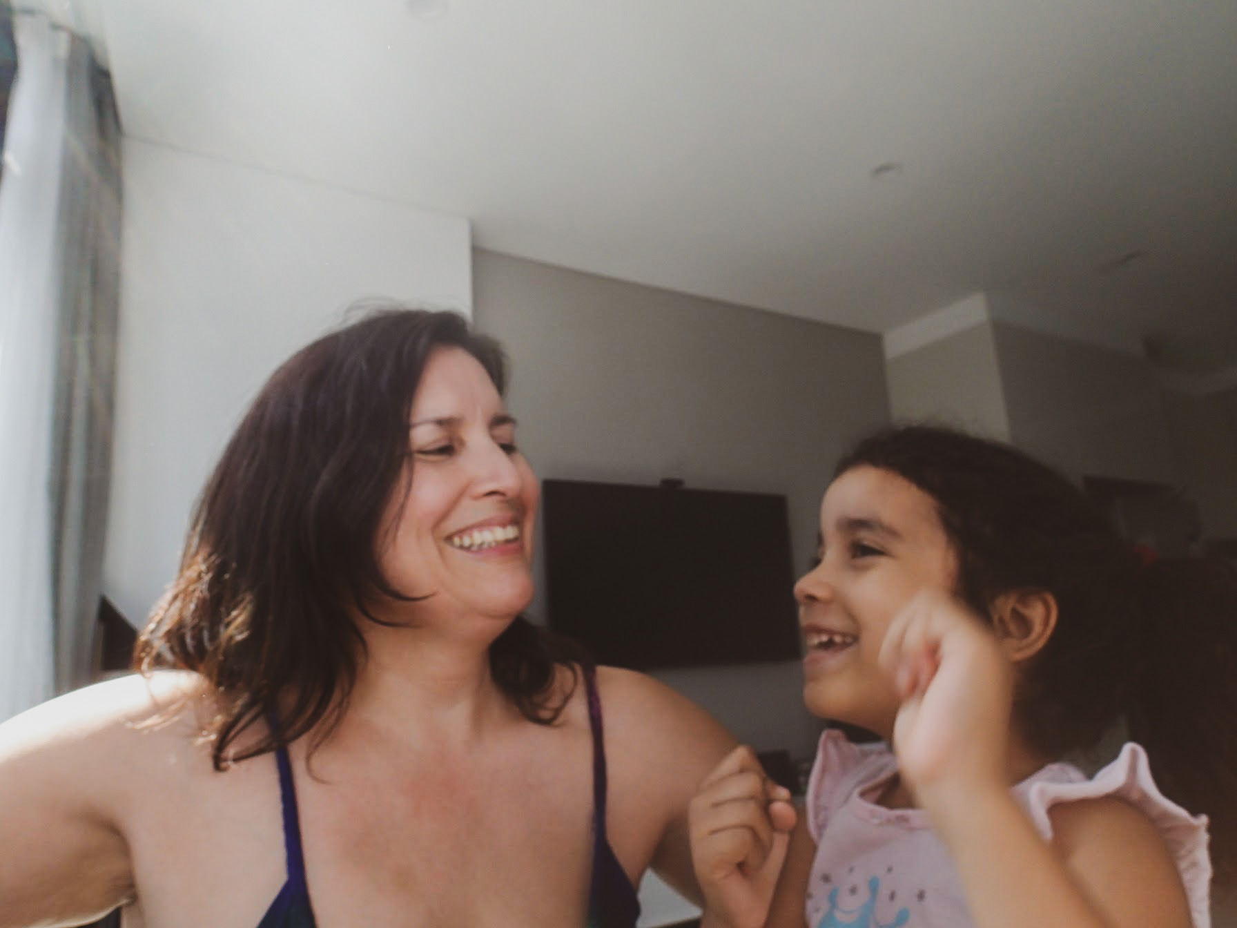 a woman wearing tank top is smiling at a small child, who is smiling back
