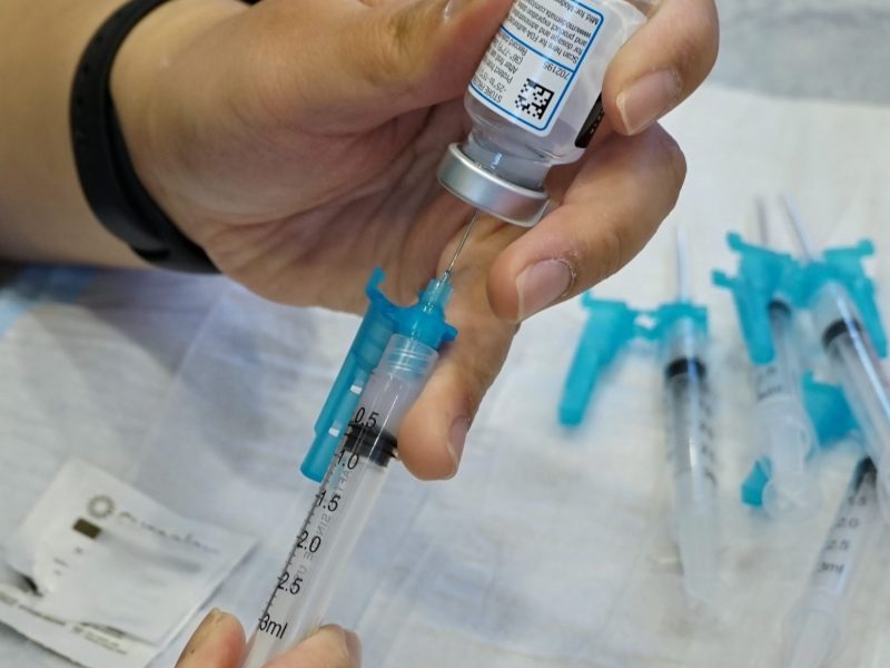 an upside down vial of the covid vaccine is put into a syringe