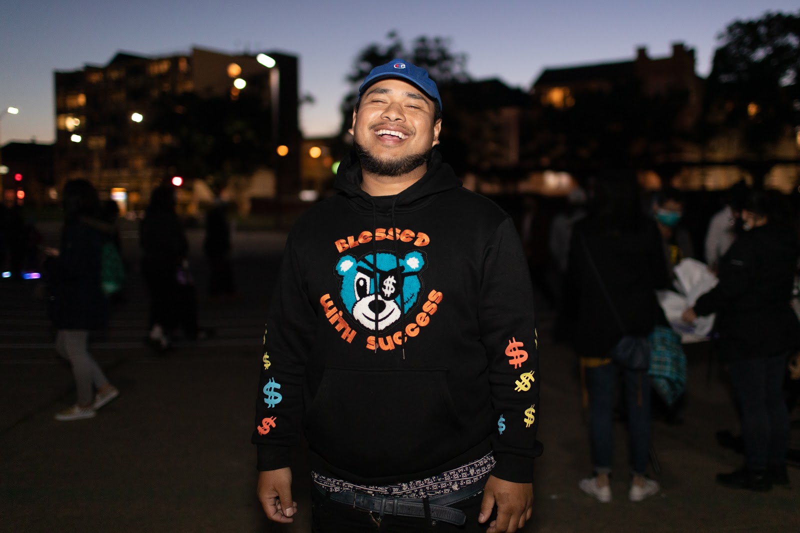 Image of a brown Asian Man wearing a cap near dusk at a park in Chinatown.