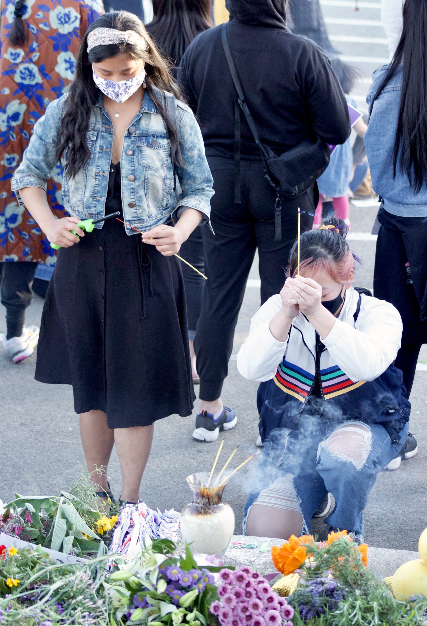 Two young Asian American women offer incense to the victims of the Atlanta shooting.