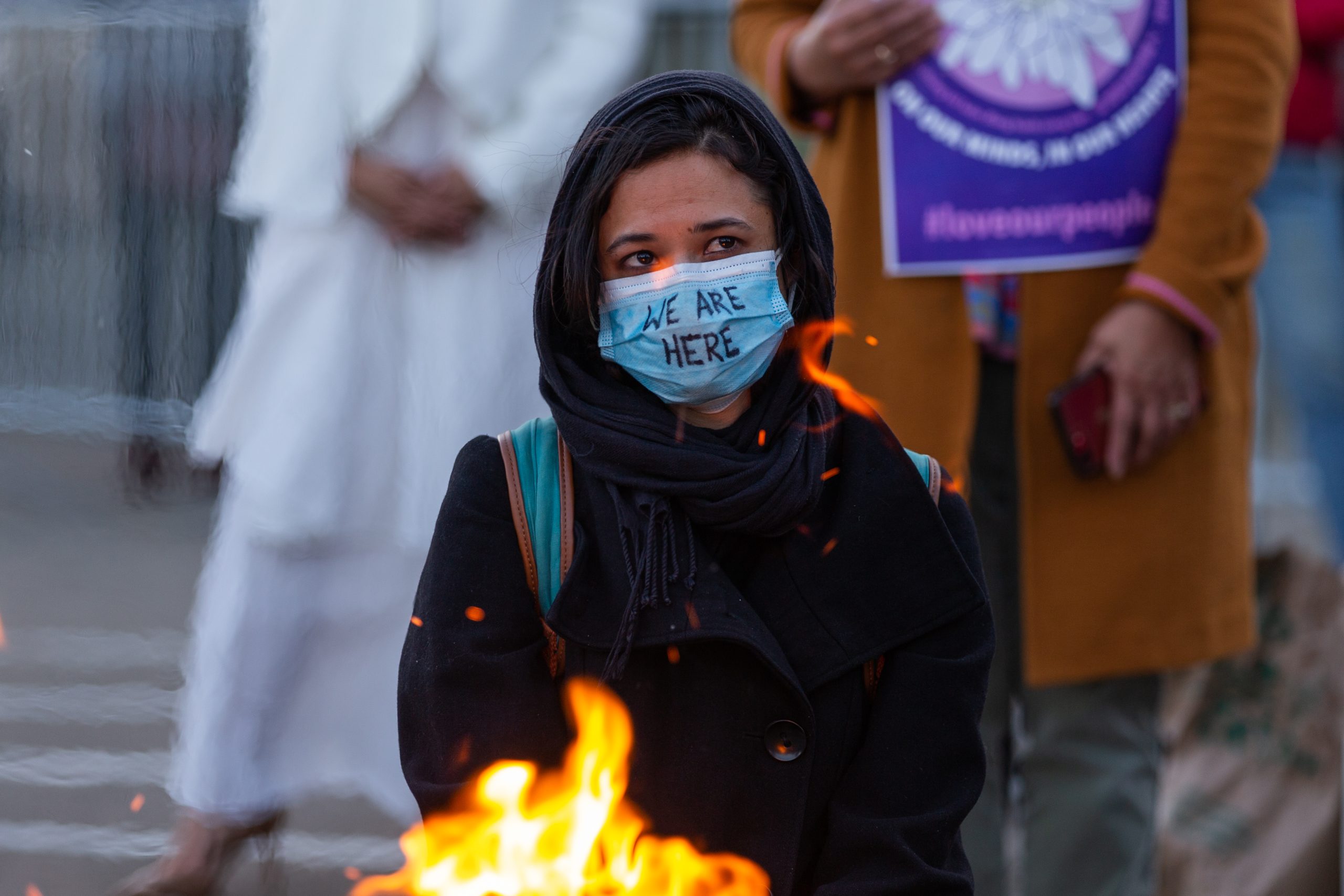 A person wearing a black hooding wears surgical mask with