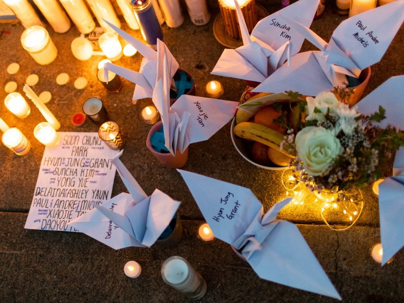 image of white paper cranes with names of Atlanta shooting victims and candles surround the cranes