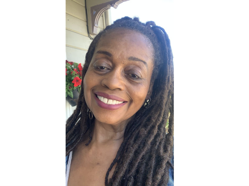 An African American woman with braids smiles for camera