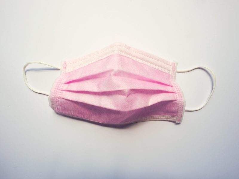 a pink surgical mask lays on a white background
