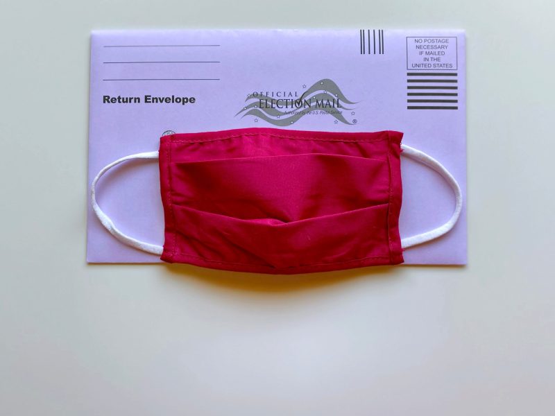 a red cloth face mask over a ballot