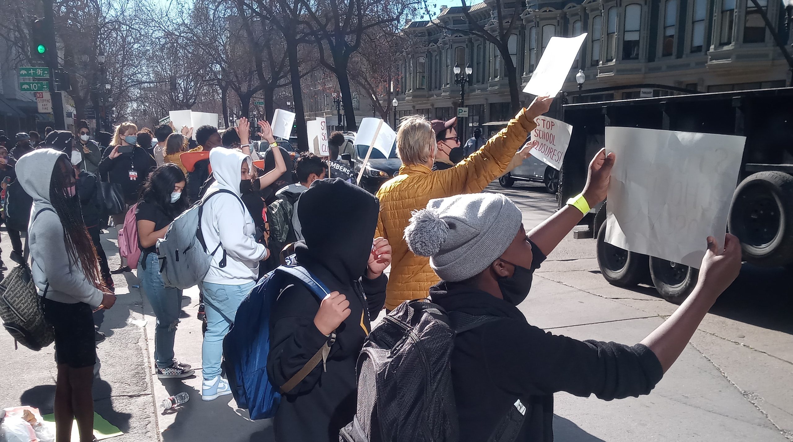 a group of people hold up signs waving at passing cars.