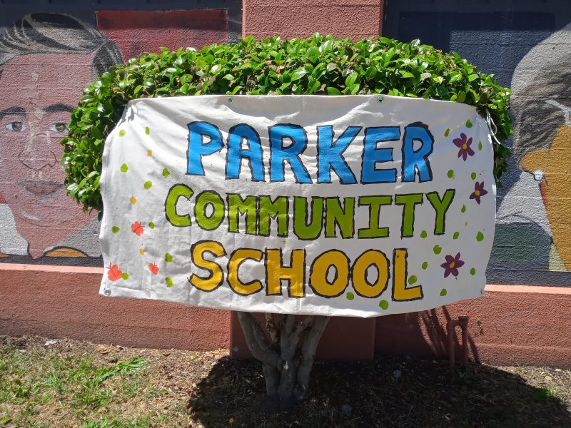 A handmade banner on white butcher paper says Parker Community School