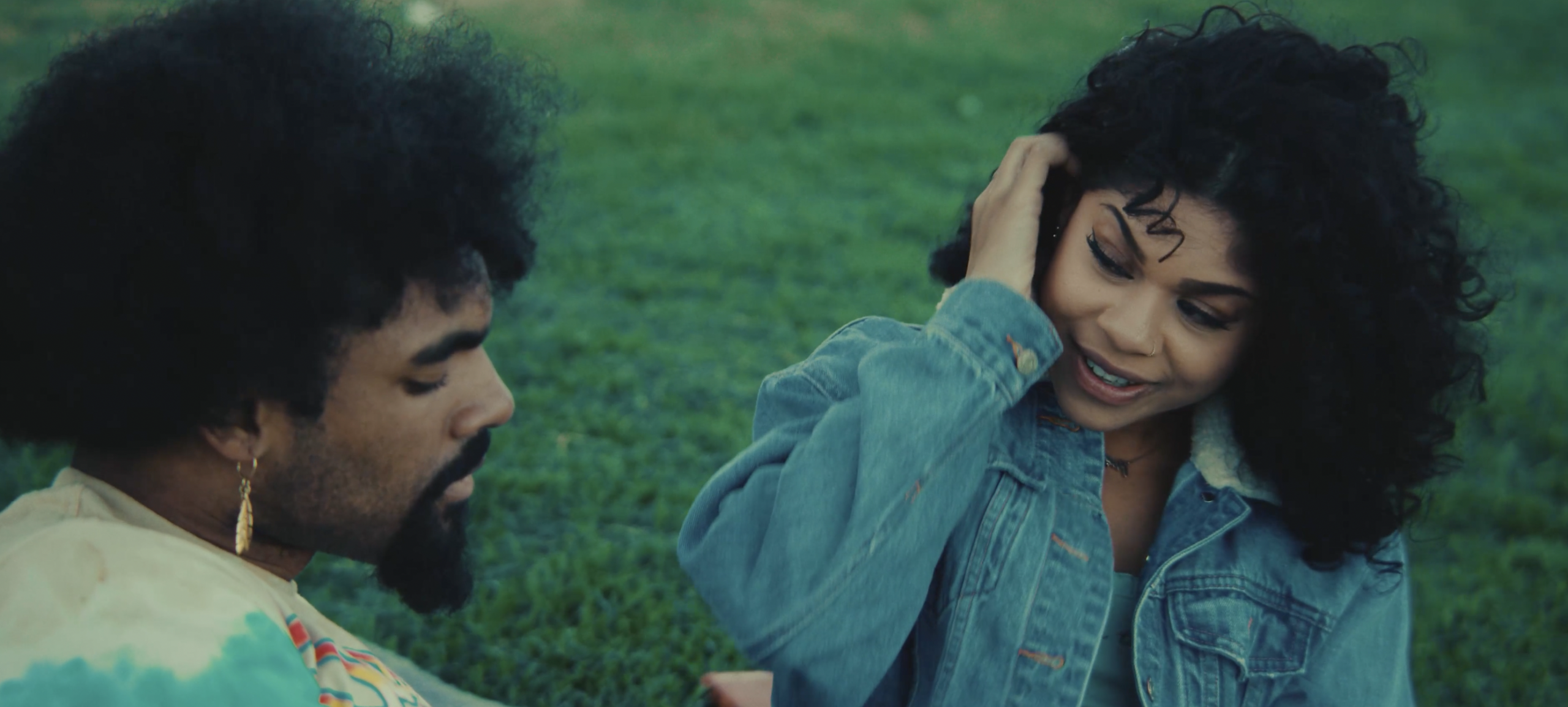 An African American man and African American woman talk while sitting in park