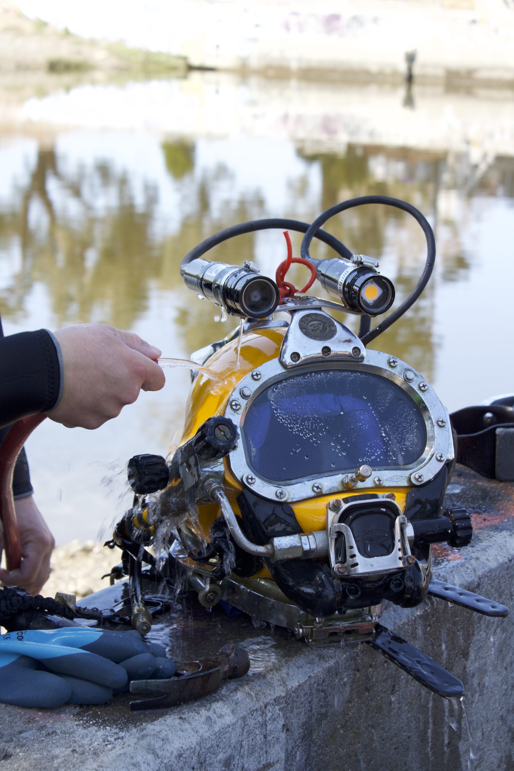 close up of an underwater helmet and a hand with a hose washing yellow helmet