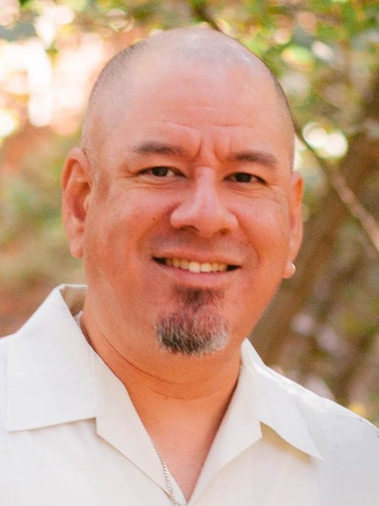 A middle aged man with goatee smiles for head shot