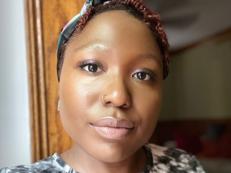 An African American woman with short hair and wearing a scarf tied around her head in a selfie