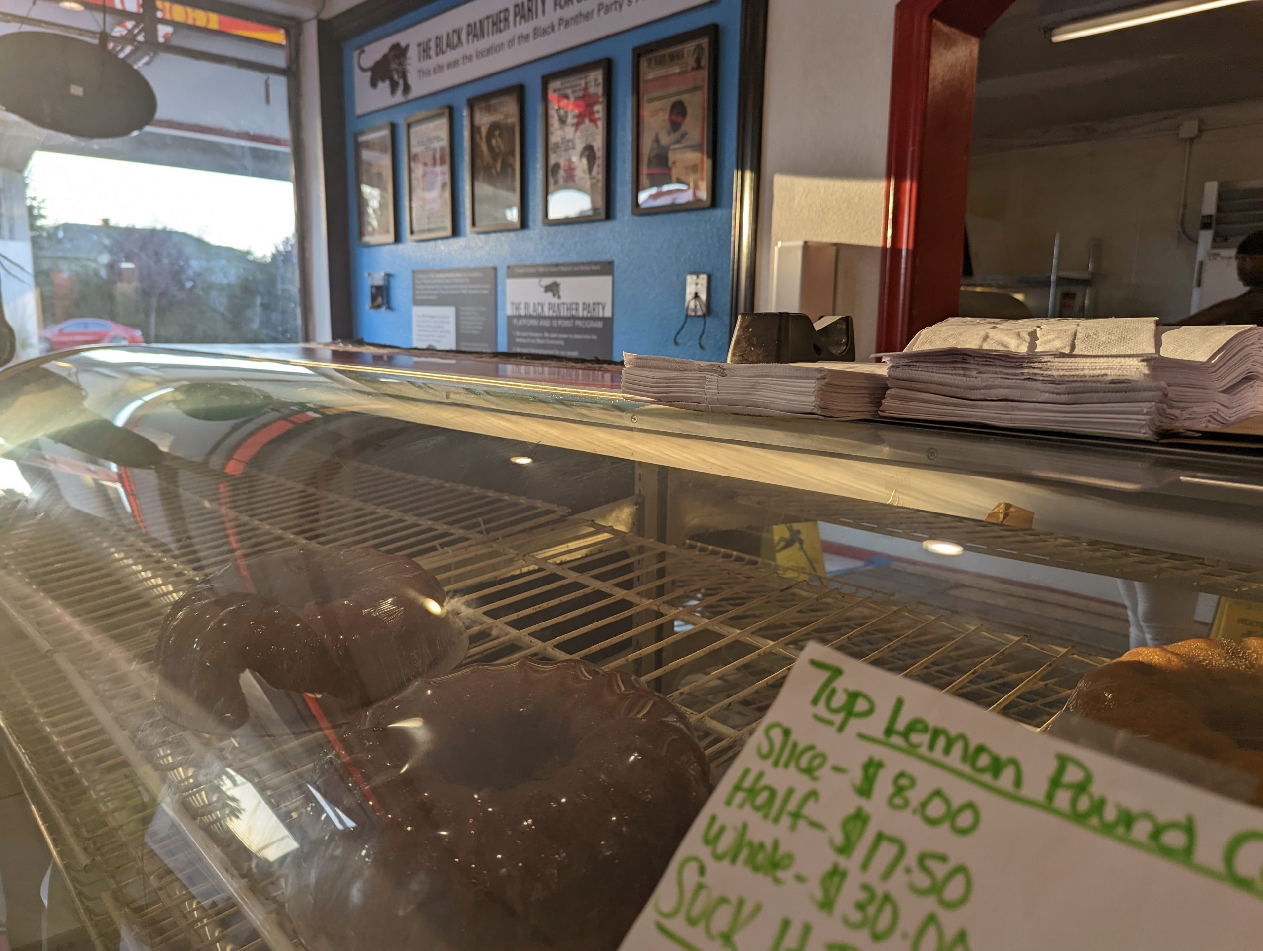 Close up up a glass case with chocolate poundcake. IN the background are images of the Black Panther Party.