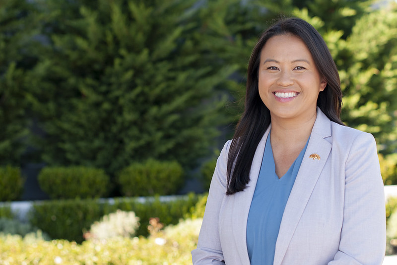 Image of Hmong American woman wearing off white blazer smiling outside