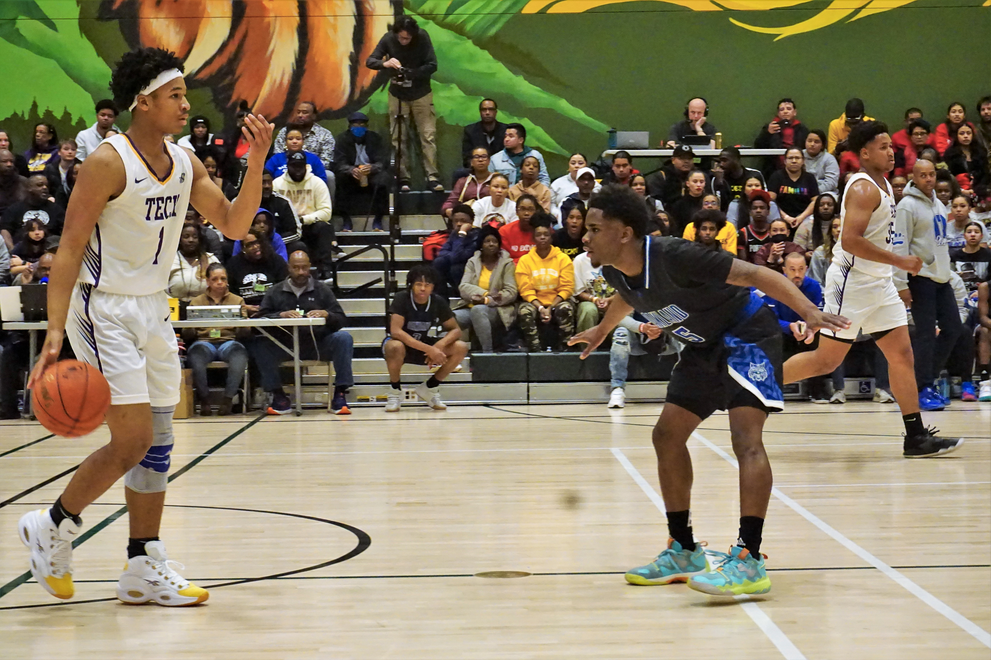 Two high school basketball players battle it out in a colorful gym