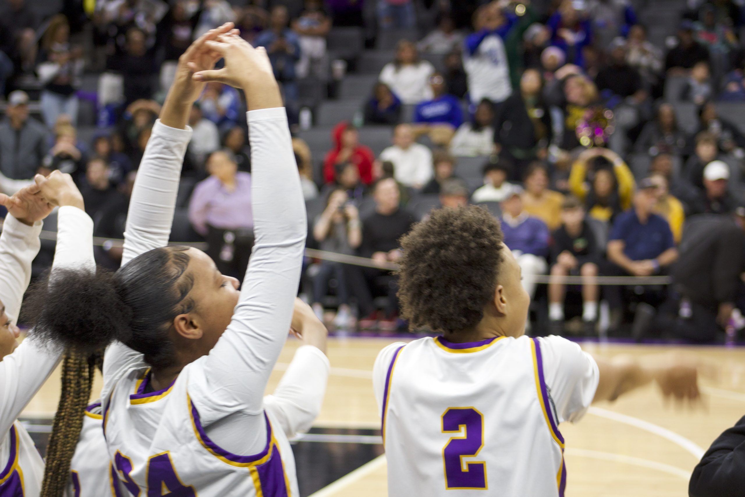 Two girl basketball players make an "O" and "T" with their arms