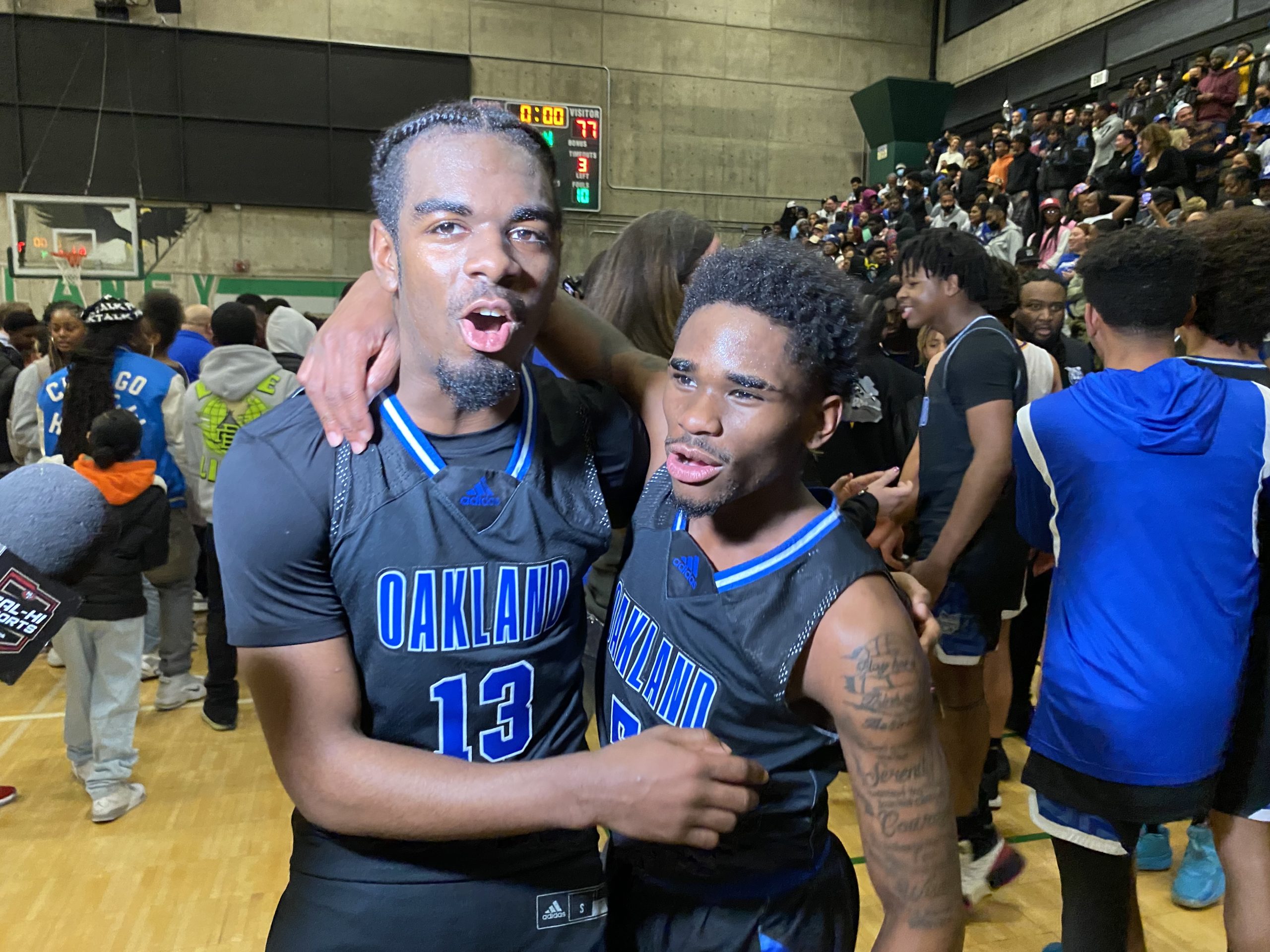 Two African American high school boys hug each other after winning a basketball championship