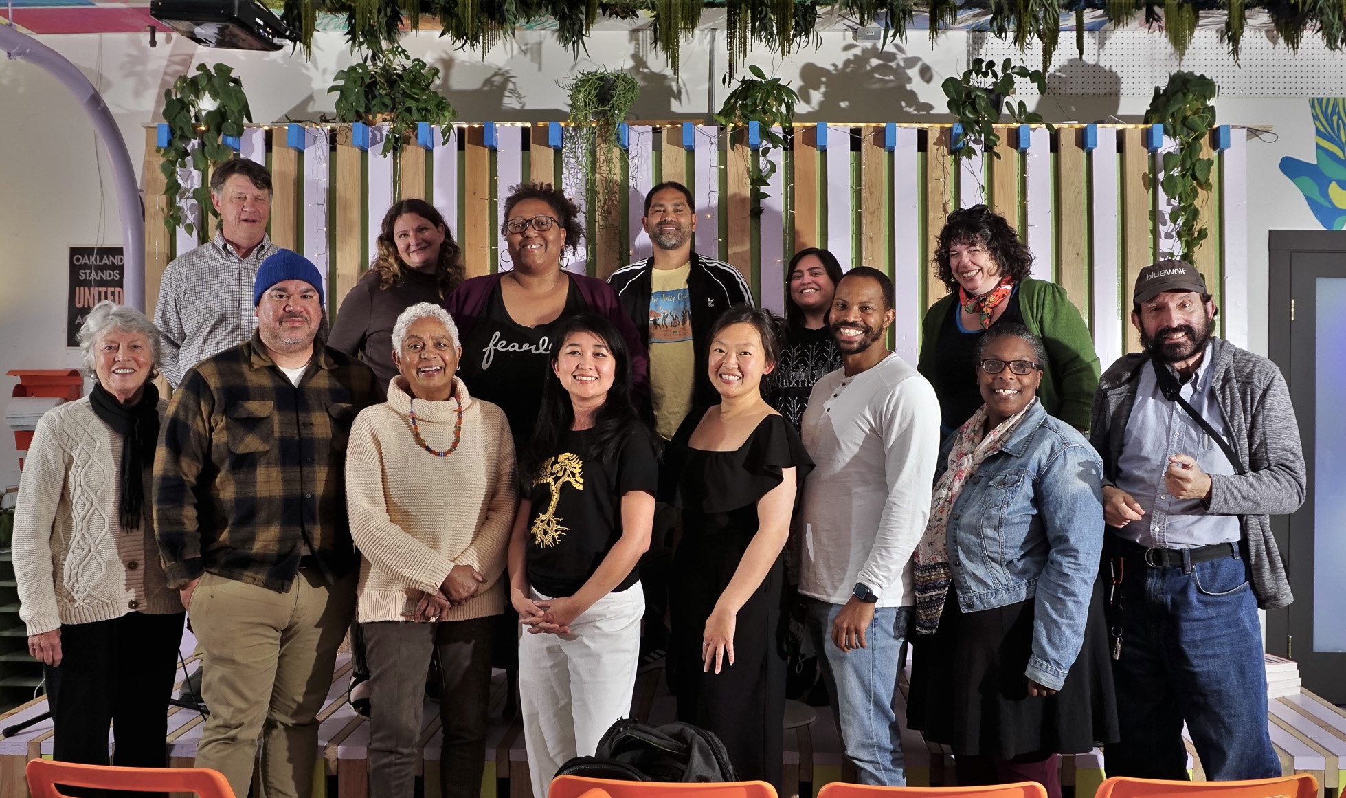 a group of diverse people of different backgrounds and ages post inside a colorful event space for a group photo