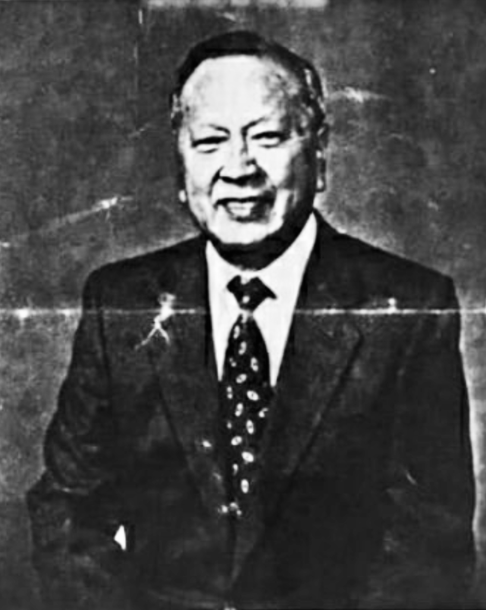 a Chinese American man smiling wearing a suit in a black and white photo