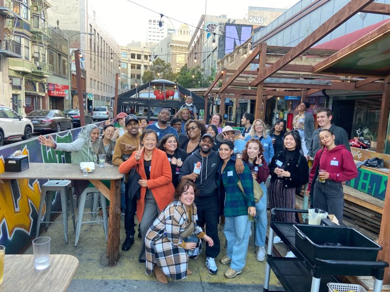 A group of diverse journalists pose for a photo in an outdoor dining area
