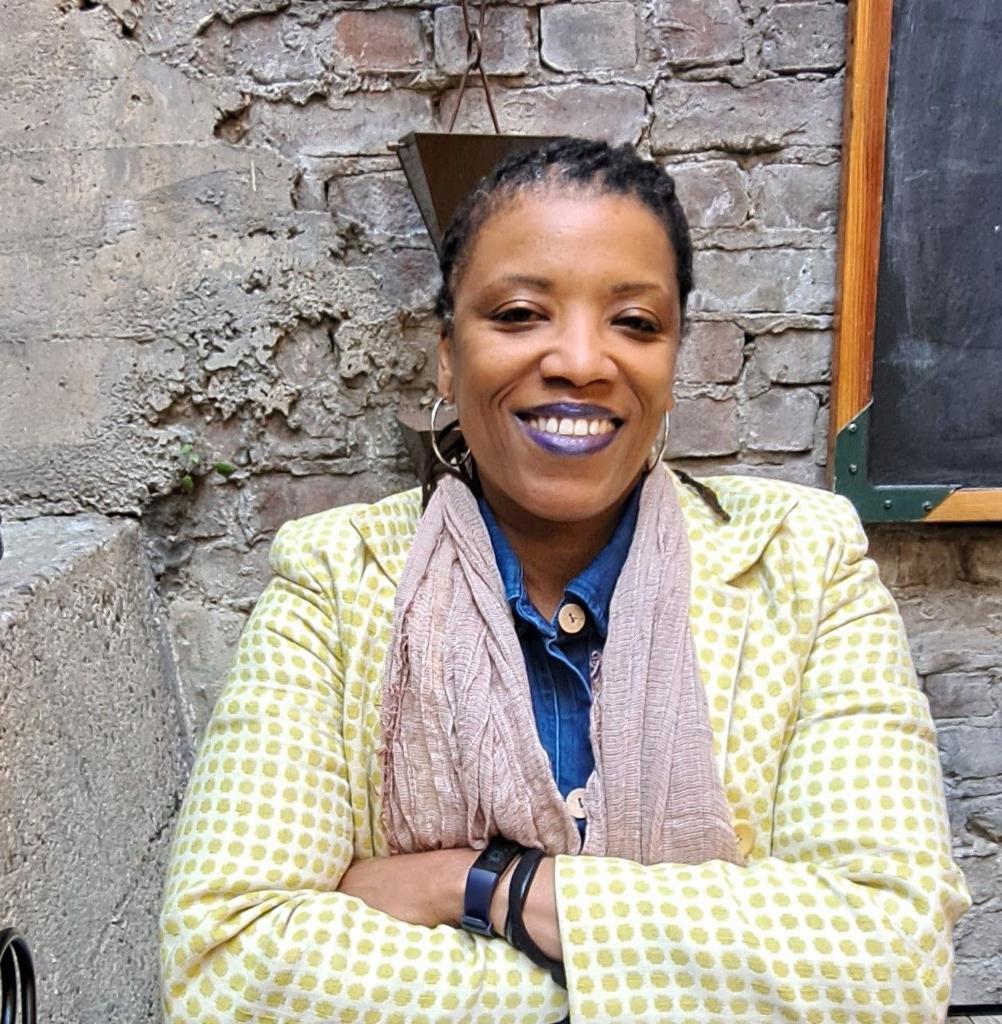 A black woman stands for a portrait