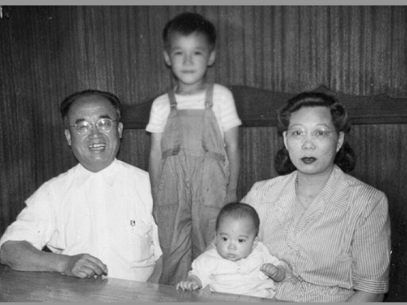 black and white photo of three Chinese American men eating inside a Chinese restaurant