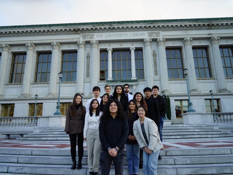 a group of diverse UC Berkeley students stand in front of a big library