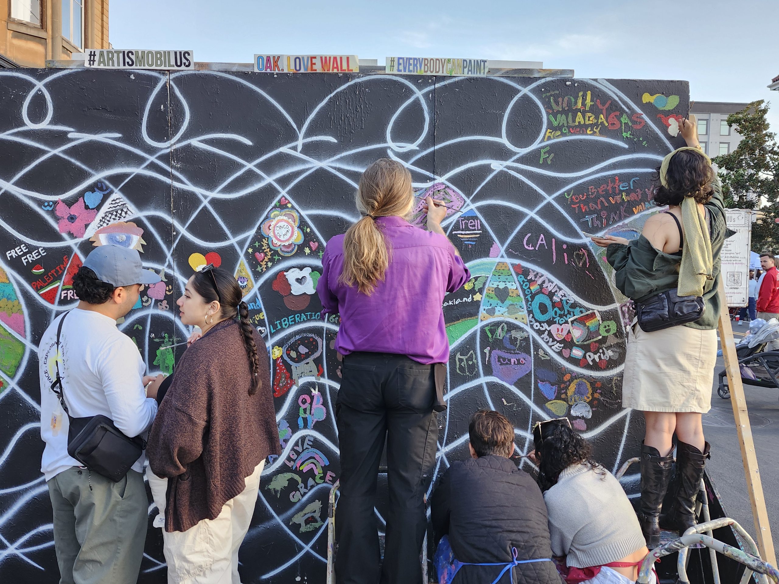 A group of people paint a mural together