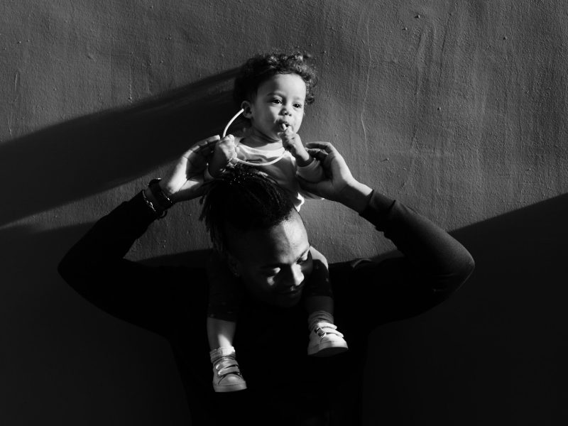 a black and white photo of a Black father holding up his child