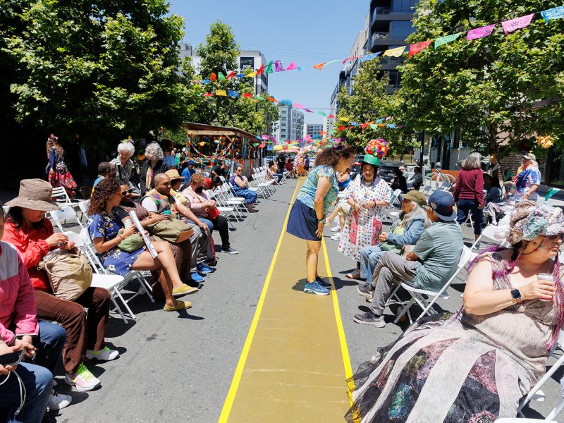 an outdoor catwalk with an audience in folding chairs outside