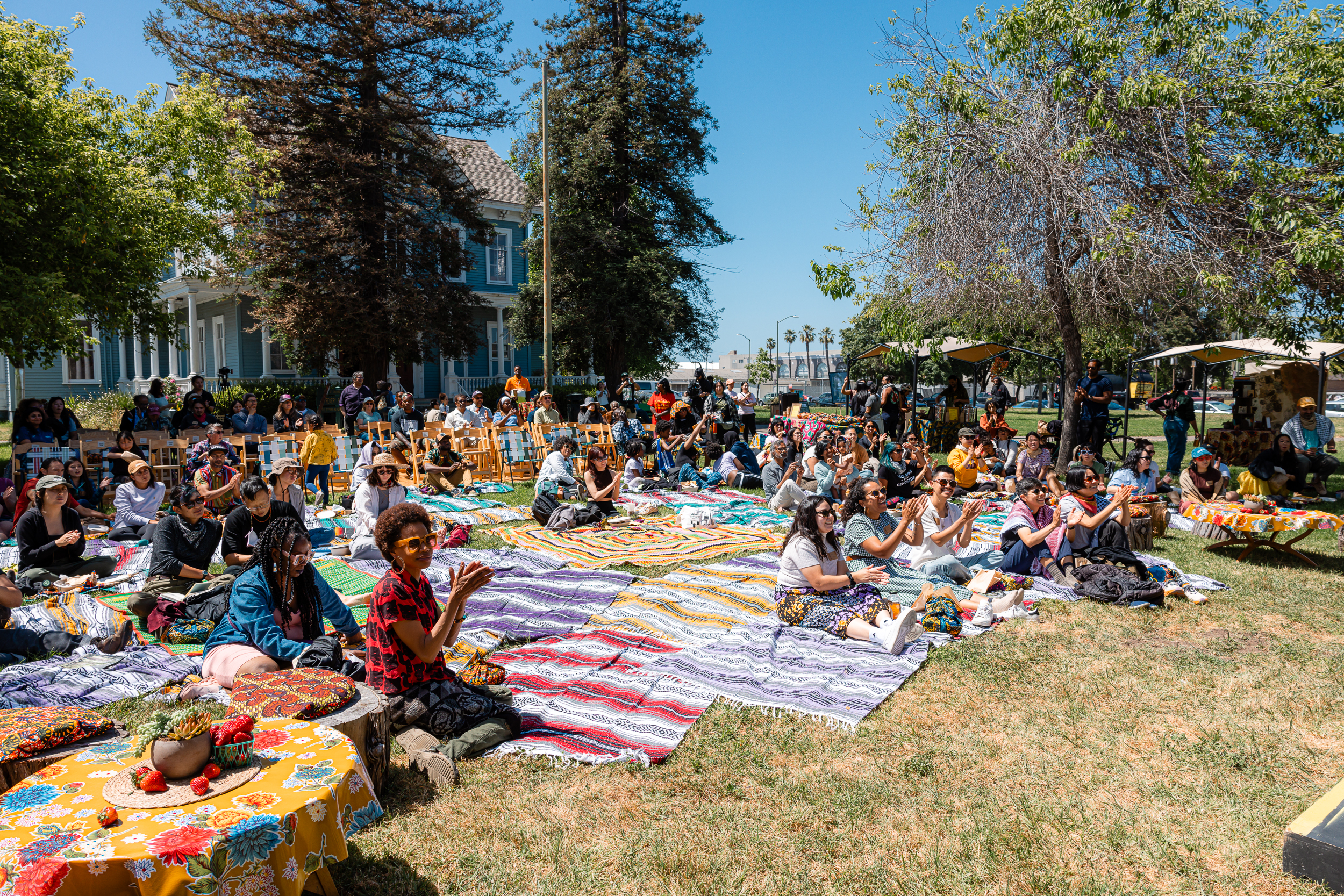 diverse people sit on ground and in chairs outside to view a film