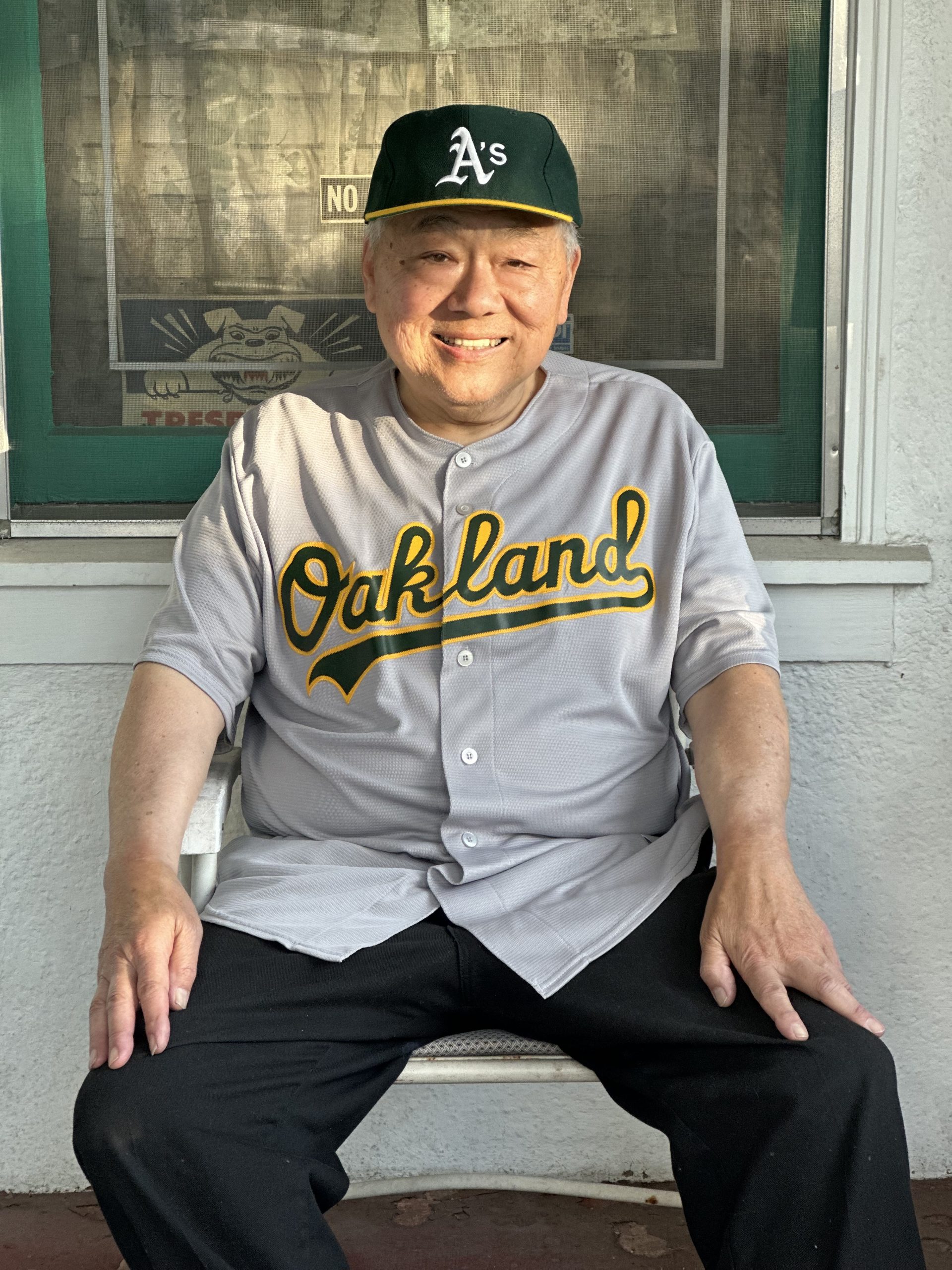 Robert Chan wears an Oakland A's hat and jersey.